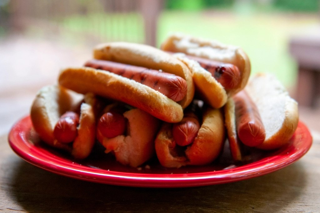 A plate of hot dogs, in buns, on a table