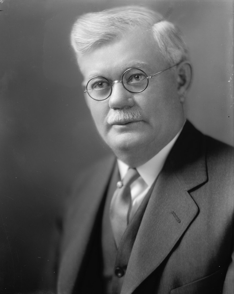 A portrait of a pale, elderly white man wearing a suit and glasses, with white hair and a neatly trimmed mustache. TOWNSEND, JOHN G. SENATOR Abstract/medium: 1 negative : glass ; 8 x 10 in. or smaller. Harris & Ewing Collection, Library of Congress. between 1905 and 1945, possibly circa 1930. Avail via Wikipedia. https://commons.wikimedia.org/wiki/File:TOWNSEND,_JOHN_G._SENATOR_LCCN2016860876_(Cropped).jpg